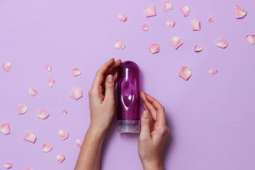 an intimate grease on a pastel background in female hands and rose petals. intimate massage. comfortable sex. 