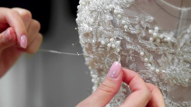 Close-up fashion designer for brides in his Studio pins needles lace wedding dress. Seamstress creates an exclusive wedding dress. Secure with pins and needles outline. Small private business. Sew