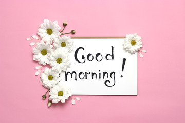 a notebook with the inscription "good morning" and a flower arrangement on a colored background. minimalism, top view. 