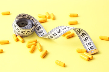 centimeter tape and pills on a colored background with space for text. concept of losing weight,...