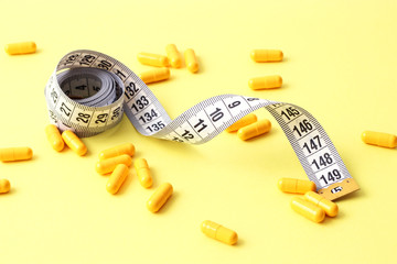 centimeter tape and pills on a colored background with space for text. concept of losing weight,...