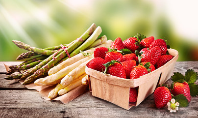Wooden punnet of strawberries with fresh asparagus