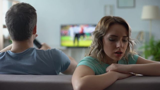 Offended girl sitting by boyfriend watching football match tv, relations crisis