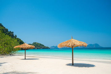 Beach Umbrella made of leafs on white beach in front of Sea day time blue sky wide shot background