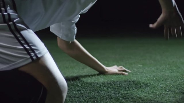 Closeup of frustrated soccer player standing on knees on field, hitting the ground with hands and scratching artificial turf after failure