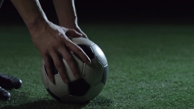 Closeup of feet of professional soccer player putting ball on field with artificial turf, kicking it and running away