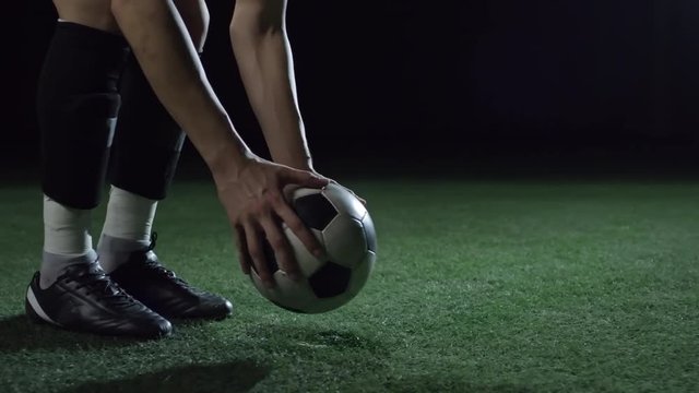 Closeup low section of soccer player putting ball on field with artificial turf, kicking it and running