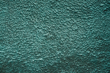 Green rough wall close-up. Background image of turquoise uneven wall.