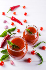 Homemade preserved ketchup in glass jars. On a white background