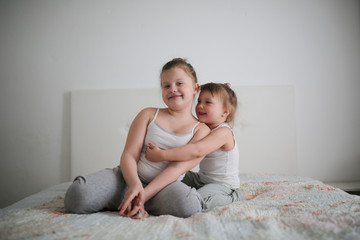 Sister girls play playfully on bed, swear and joke