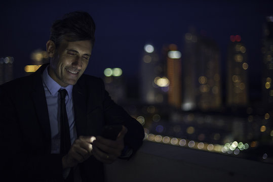 Businessman on high rise rooftop using mobile phone