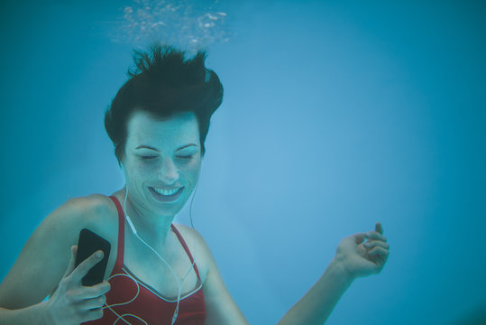 Woman listening to music with smartphone underwater