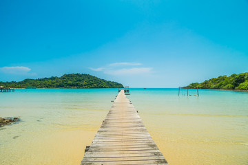 Fototapeta premium Wooden pier or bridge with tropical beach and sea in paradise island