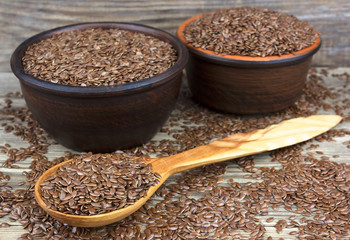 Flax seeds in bowl with scattered grains on wooden background wi