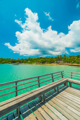 Fototapeta na wymiar Wooden pier or bridge with tropical beach and sea in paradise island