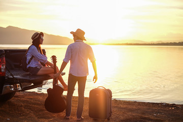 couple traveler playing guitar and watching sunset near the lake background  the mountain.Asia tourist enjoying for sunset during holiday