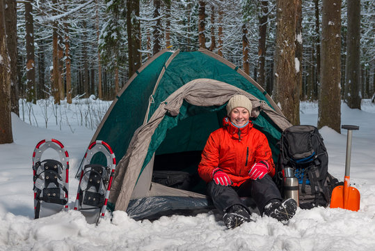 happy active tourist sits in winter forest in tent