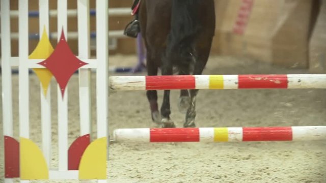 Young rider on black horse galloping at show jumping competition