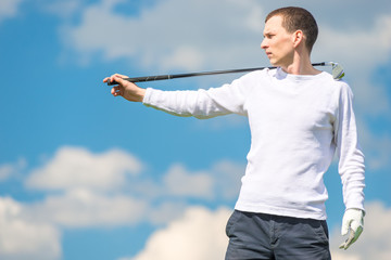 Fototapeta na wymiar serious golfer professional posing with golf club on blue sky background