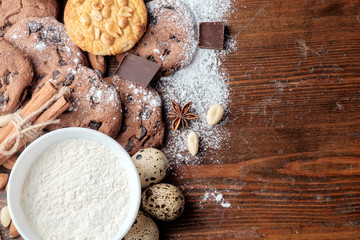 Chocolate chips cookies, cookies with peanuts and scattered nuts on dark rustic texture with place for your text. Top view. Flat lay.