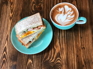 Fresh sandwich and swan shape Latte art coffee cup on the wooden   table. Delicious Breakfast , Natural Light. 