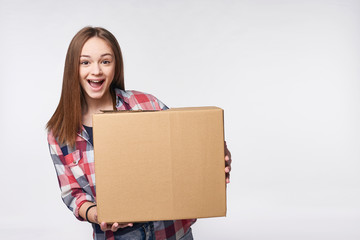 Delivery, relocation and unpacking. Excited young woman holding cardboard box, looking at camera, surprised, isolated