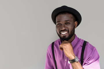 portrait of handsome smiling african american man in stylish hat isolated on grey