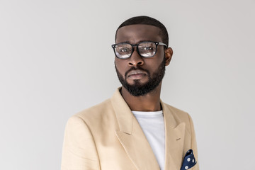 portrait of handsome young african american man in eyeglasses looking at camera isolated on grey