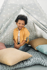 little smiling african american boy sitting in teepee at home © LIGHTFIELD STUDIOS
