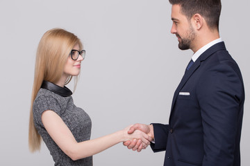 Young businesspeople handshake on gray background