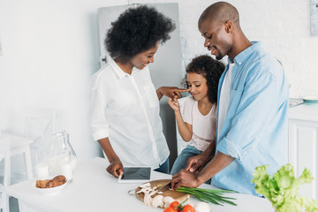 african american man cutting fresh vegetables for breakfast with family standing near by in kitchen at home