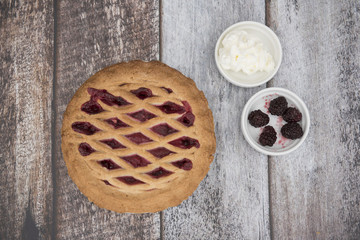 Blackberry and apple pie with fruit and cream on a wooden background 