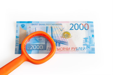 Two thousand roubles banknotes and a magnifying lens. Isolated on white background.
