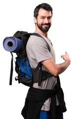Handsome backpacker pointing back on white background