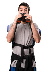 Handsome backpacker with binoculars on white background