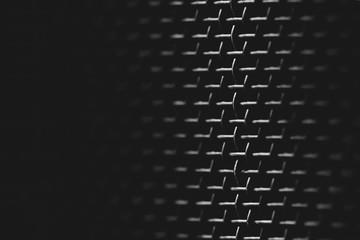 Background image of shiny mesh on dark backdrop. Metallic texture of grid close-up. Triangular shape of grid. Abstract image of surface of audio speaker in macro photography. Futuristic design.