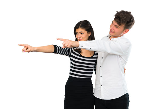 Young couple pointing finger to the side and presenting a product on isolated white background