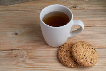 Oatmeal cookies with sunflower seeds near cup of tea.