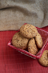 homemade oat cookies with sunflower seeds in and near red checkered basket on wooden table