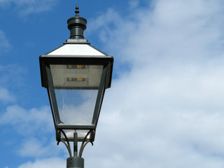 Fototapeta na wymiar LED street lamp isolated on cloudy blue sky background. Vintage lantern with modern lighting technology