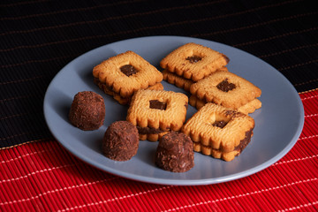 Chocolate cookies on gray plate on style red and black table, closeup.