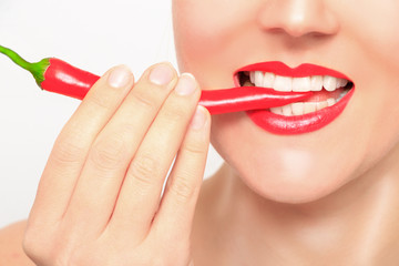 Beautiful woman teeth eating red pepper