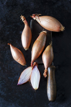 Sliced and whole banana shallots and an old cleaver