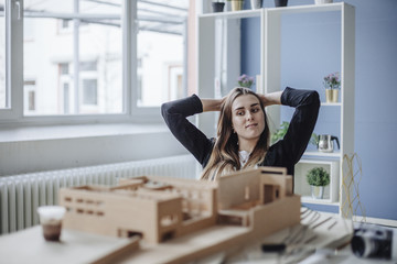 Portrait of young architect looking at architectural model in office