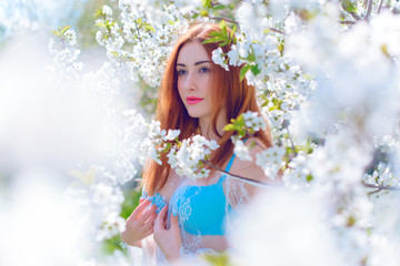 Young girl in the blossom of trees in a romantic transparent lace bohemian dress. The concept of romance and purity 