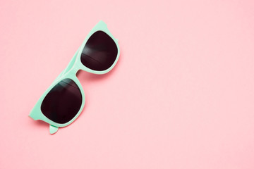 Green pastel sunglasses isolated on punchy pink, top view. Copy space. Summer concept.