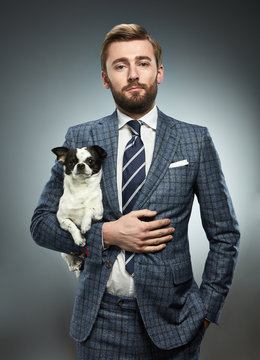 A man in a business suit with a chihuahua.