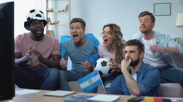 Multiracial Agrentinian friends watching game at home, celebrating goal chanting