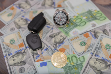 Car key, chronograph and gold bitcoin on Euro and Dollars banknotes background