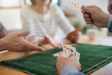 Senior friends at home playing cards